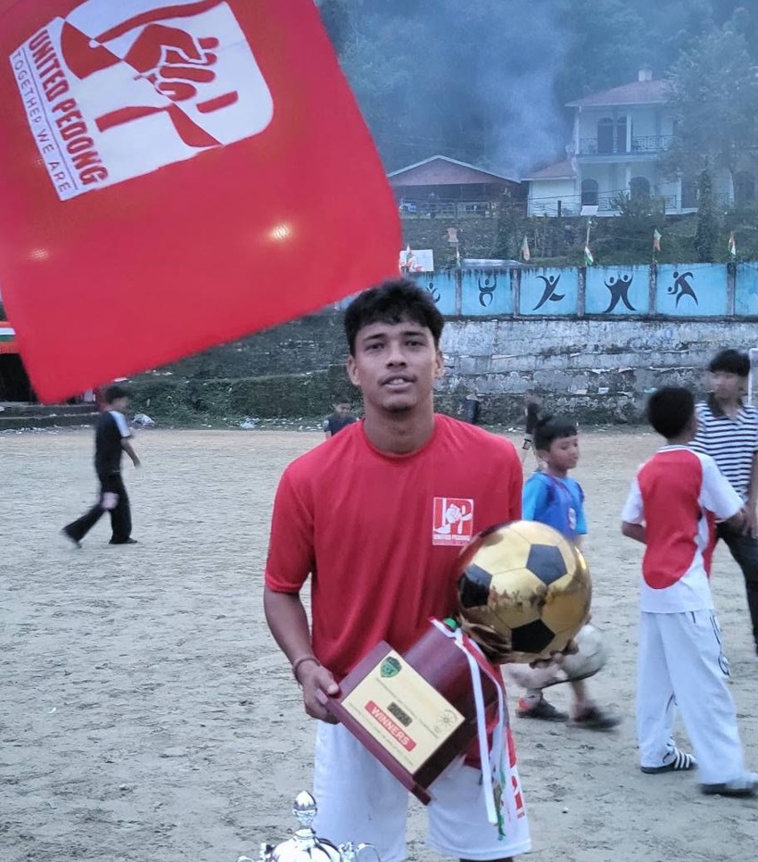 United Pedong player holding club flag and trophies